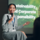 A smiling speaker during a corporate sustainability conference, with a presentation in the background highlighting the importance of corporate responsibility.